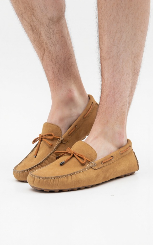 A male model wearing Moccasins, against a white background, with a close   up of the feet